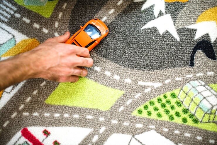 Jouer avec des voitures en miniature sur un tapis circuit de voiture