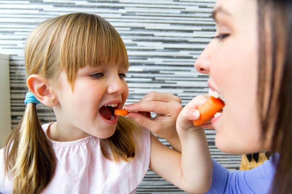 Maman et une petite fille mangent des carottes