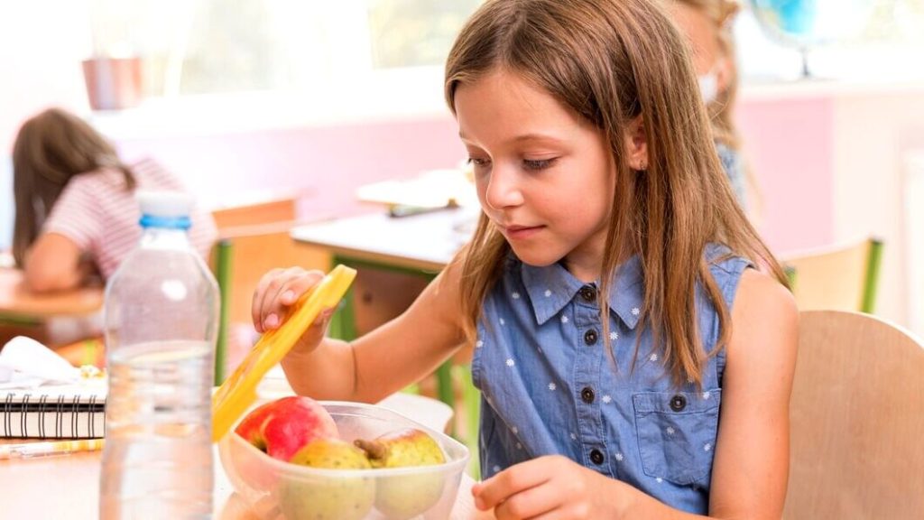 Petite fille mangeant une collation de fruits