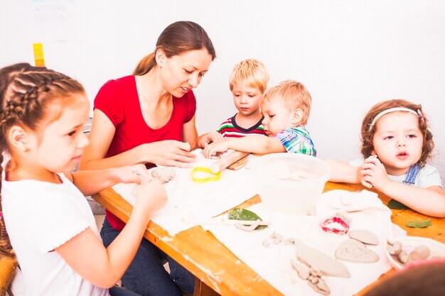 Femme joue avec des enfants à la crèche