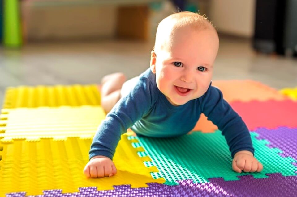 Bébé souriant sur un tapis en mousse