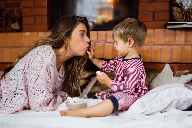 Maman joue avec son enfant au lit